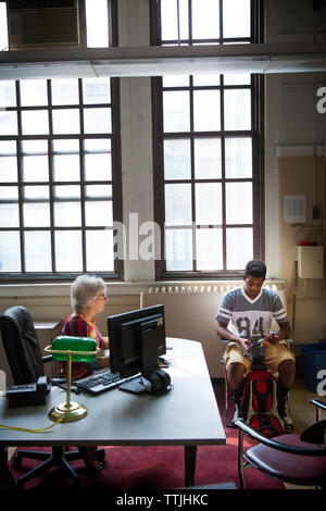 Teenage boy sitting with school principal in office Stock Photo