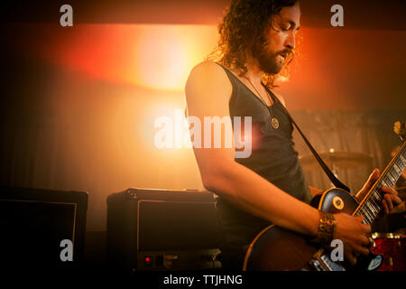Man practicing guitar in rock music studio Stock Photo