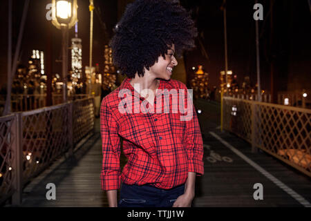 Smiling woman looking away while standing on Brooklyn Bridge Stock Photo