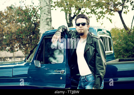 Confident man leaning on pick-up truck door Stock Photo