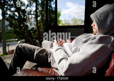 Man using smart phone while relaxing at porch Stock Photo