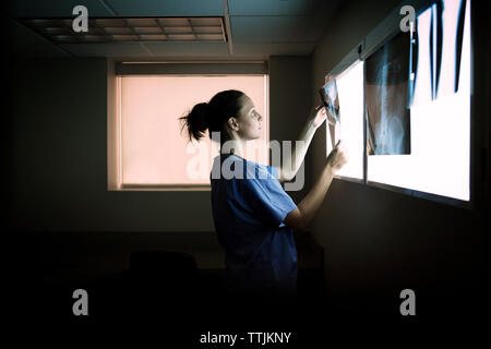 Side view of doctor examining x-rays on diagnostic medical tool in hospital Stock Photo