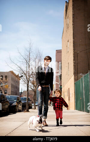 Portrait of father holding daughter's hand while walking with dog on footpath Stock Photo