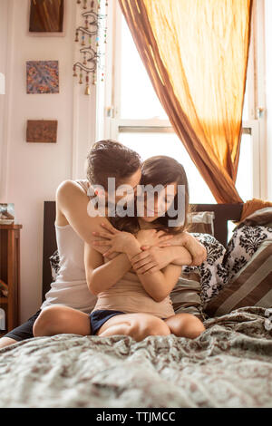 lesbians romancing while sitting on bed at home Stock Photo