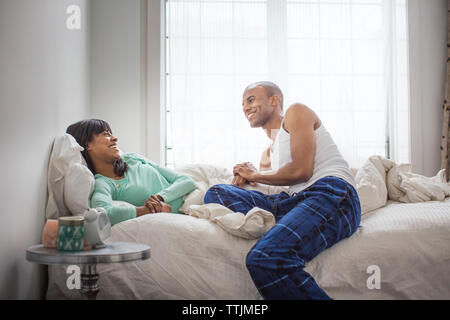 Smiling couple talking while relaxing on bed at home Stock Photo