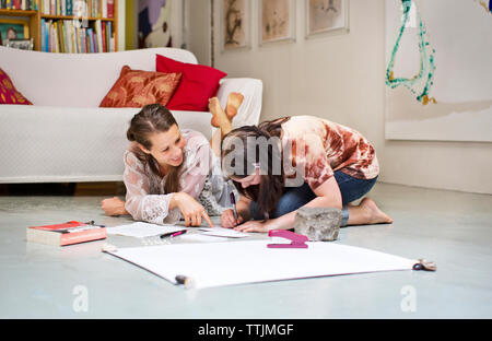 Mother teaching daughter while lying floor at home Stock Photo