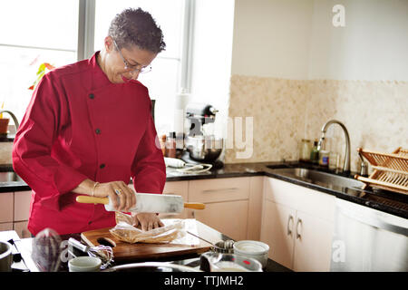 Woman crushing tart ingredient with rolling Pin while working in kitchen at home Stock Photo