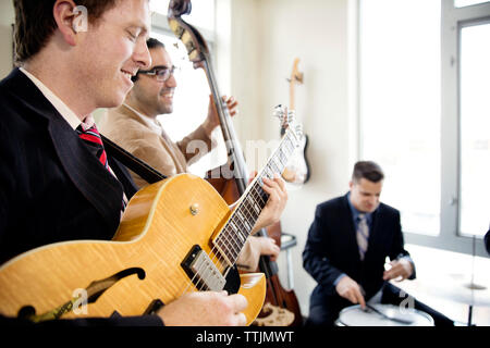Smiling men practicing in music studio Stock Photo