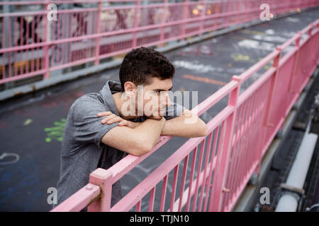 High angle view of thoughtful man leaning on railing at footbridge Stock Photo