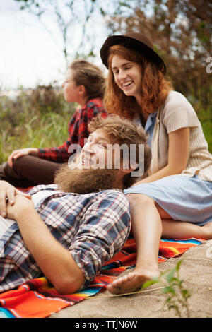 Smiling friends relaxing on field Stock Photo