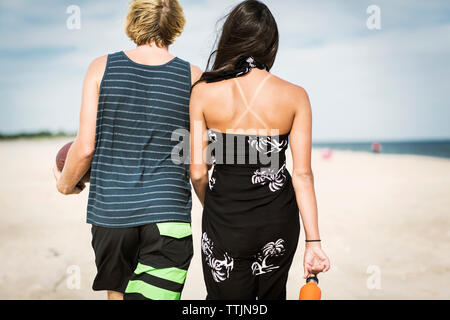 Rear view of couple walking on sand at beach Stock Photo