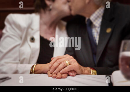 Midsection of senior couple kissing while sitting in restaurant Stock Photo