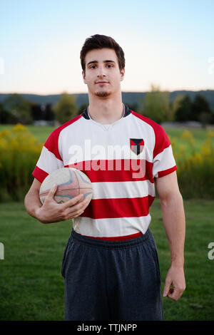 Portrait of player holding rugby ball on field against clear sky Stock Photo