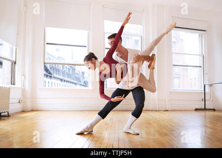 Full length of graceful male and female ballet dancers performing in studio Stock Photo