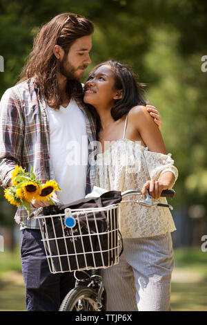 Thoughtful loving couple standing with bicycle at park Stock Photo
