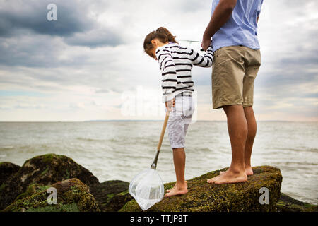 Portrait of smiling daughter fishing with father while sitting by