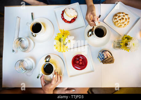 Cropped image of friends having coffee and dessert at table in restaurant Stock Photo