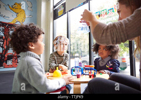 Teacher showing science experiment to children at preschool Stock Photo