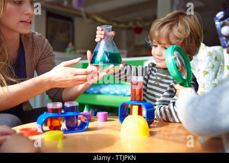 Teacher guiding students in doing science experiment at preschool Stock Photo