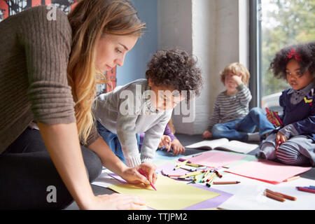 Teacher drawing with students on floor at preschool Stock Photo