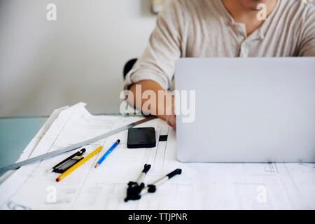 Midsection of man using laptop at table in office Stock Photo