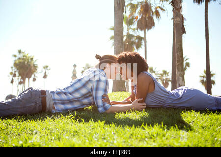 Side view of couple lying on grassy field Stock Photo