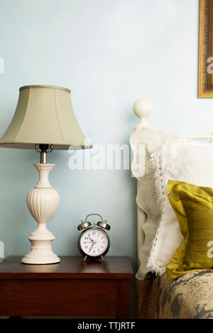 Alarm clock and lamp on side table in bedroom Stock Photo
