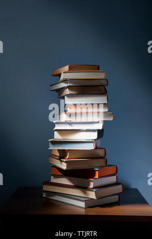Stack of books on wooden table in darkroom Stock Photo