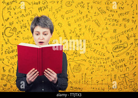 Stunned woman reader looking amazed in a book. Mathematics calculations, economics formula and equations difficult to solve. Ideas and planning concep Stock Photo