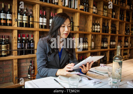 Woman using tablet computer while sitting in restaurant Stock Photo