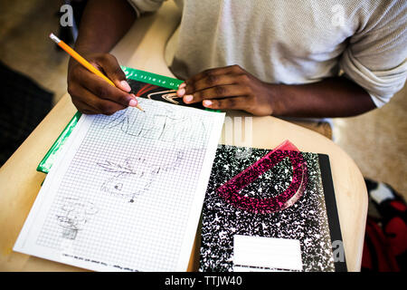 High angle view of teenage boy drawing on graph paper in classroom Stock Photo