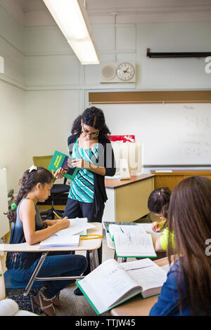 Teacher looking at student while teaching in classroom Stock Photo