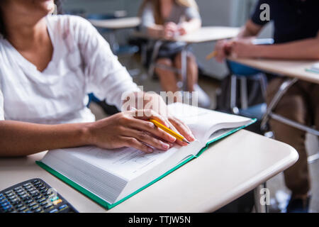 Midsection of woman with book in classroom Stock Photo
