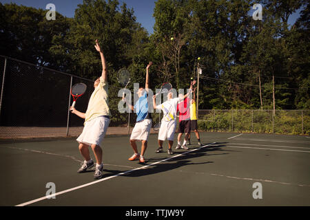 Players standing in row playing tennis at court Stock Photo