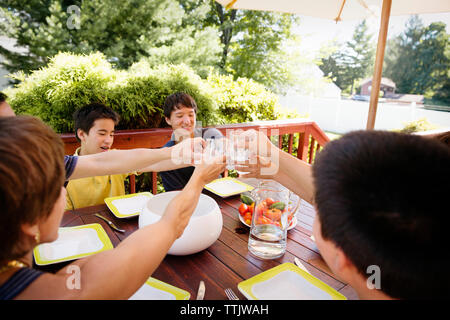 High angle view of family toasting drinking glasses while having food at porch Stock Photo