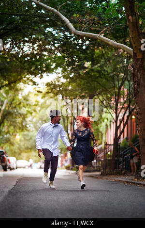 Happy couple holding hands and running on street Stock Photo