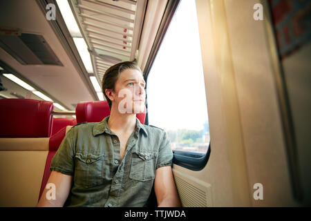 Man looking through window while traveling in train Stock Photo