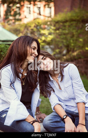 Smiling mother and daughter resting at park Stock Photo