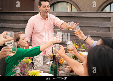 Friends toasting wineglasses while enjoying meal at table Stock Photo