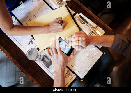 Overhead view of man using smart phone while sitting with girlfriend in restaurant Stock Photo