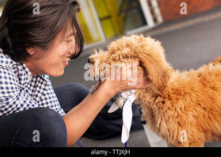 Side view of man holding poodle while crouching on road Stock Photo