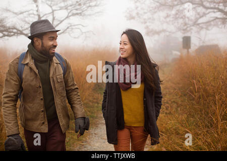 Couple talking while walking in forest Stock Photo