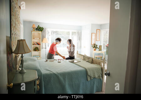 Women looking at jewelries while sitting on bed Stock Photo