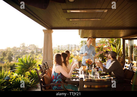 Friends talking while having drink at table at porch Stock Photo