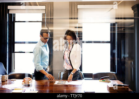 business people reading document while standing by desk in office seen through glass Stock Photo