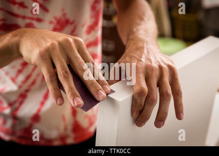 Cropped image of man polishing frame with polish paper in workshop Stock Photo