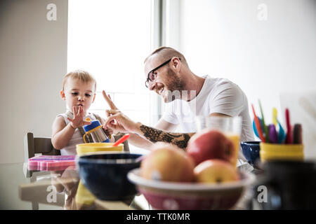 Father gesturing while teaching daughter at breakfast table Stock Photo