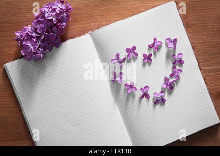 Lilac flowers in a heart shape on open white book Stock Photo