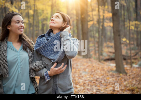 Happy daughter and mother walking amidst trees in forest Stock Photo