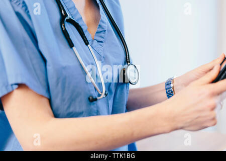 Midsection of female doctor using tablet computer while standing in hospital Stock Photo